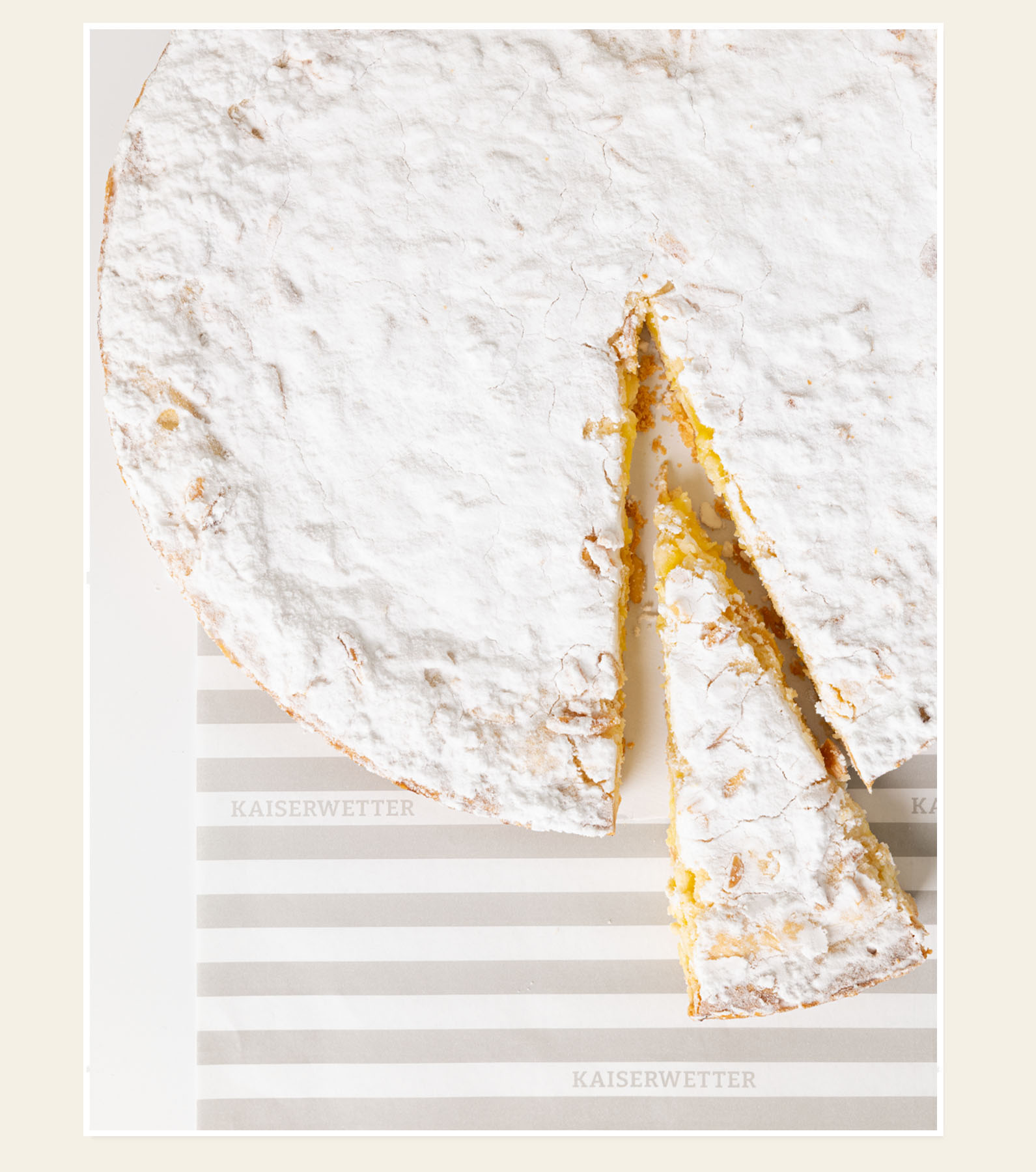 Puderzuckerkuchen, angeschnitten, auf Kaiserwetter-Papier
